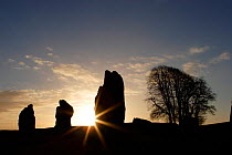 Sunrise over three stone megaliths at Avebury Stone Circle (World Heritage Site) Avebury, Wiltshire, UK