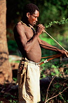 Hadzabe bushman holding traditional bow and arrow with two hunted ground squirrel tucked under belt, Lake Eyasi, Tanzania.