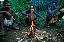 Three Hadzabe bushmen squatting round fire, preparing to cook. Lake Eyasi, Tanzania.