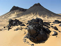 Shiny black volcanic rock strewn over the sand in the Black Desert, Western-Egypt.