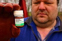 Pest controller with a bottle of Strychnine, used for killing moles {Talpa europaea} UK.
