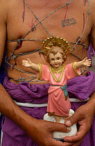 Cucurucho carries statue of Jesus and wraps barbed wire around his chest to share in suffering. Good Friday parade, Quito, Ecuador.