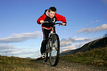 Young boy riding mountain bike, Cairngorms National Park, Scotland, UK Model released.