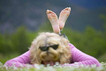 Woman lying barefoot in field of daisies, enjoying nature on a summer day, Cairngorms National Park, Scotland, Europe Model released.
