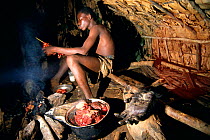 Hunter smoking gorilla meat for transportation to market, Central Africa. The intestines and organs are consumed at camp.