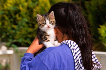 Domestic cat being carried on woman's shoulder