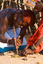 Samburu warriors starting a fire using traditional methods of spinning a stick between the hands causing friction and fire. Kenya, Africa. 2005.