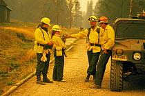 Photographer's family and pet cat with fire fighters discuss protection of wood cabin, Yellowstone NP, Wyoming, USA. 1988