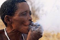 Jo / Hoan bushman smoking traditional pipe, Bushmanland, Namibia. 1996