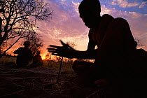 Jo / Hoan bushman making fire by traditional method of turning sticks, Bushmanland, Namibia. 1996