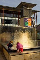 Children play in the water feature at At Bristol Science Museum, Millenium Square, Bristol, UK. 2006
