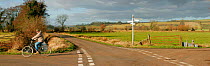 Cyclist on quiet country crossroads, near Wells, Somerset Levels, UK.