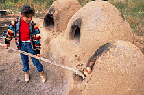Native American child baking bread in clay oven, Taos Pueblo, New Mexico, USA