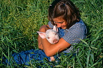 Girl holding Domestic piglet {Sus scrofa domestica} Mixed Breed, USA