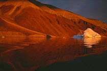 Coastal landscape and small iceberg in midnight summer sun, Qaanaaq, Greenland