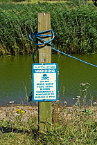 Sign warning of toxic Algal bloom, Slapton Ley NNR National Nature Reserve, Devon, England, 2006.  Note green water colour.
