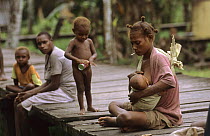 Asmat woman nursing baby whilst smoking, Western Papuasia, Indonesia (Formerly Irian Jaya) 2002 (West Papua).