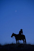 Silhouette of Cowboy looking up at crescent moon, Shell, Wyoming, USA