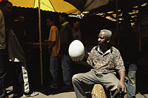 Market trader holding egg of extinct Giant elephant bird {Aepyornis maximus} Madagascar, 2004
