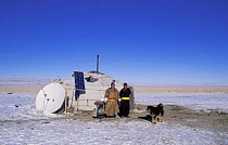 Nomadic tribal people outside their traditional yurt with modern satellite dish and solar panels, Gobi Desert, Mongolia, January 2004. Filmed for BBC Planet Earth series.
