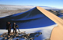 People standing at top of sand dune, filming across Gobi Desert in winter with snow, Mongolia, for BBC Planet Earth series, January 2004.