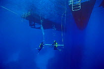 Divers rest at safety stop bar under diving boat,  Coral sea, Australia