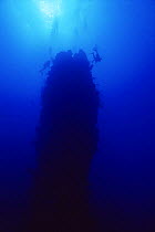Divers at the 'Eye of the needle', underwater rock pinnacle, Saba, Caribbean