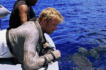 Producer Mark Brownlow in metal chain dive suit, watching Grey reef sharks from boat, Bikini Atoll, Marshall Islands, August 2003. BBC Roboshark programme