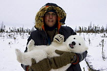 Polar Bear {Ursus maritimus} anaesthetised 3/4-months cub held by biologist Nick Lunn during examination, Wapusk NP, Manitoba, Canada