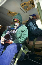 Doug Allan, cameraman, filming for BBC 'Andes to Amazon' wearing oxygen mask for filming aerials out of the open door of Cessna plane at 6500m, Bolivia, 1997