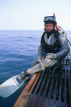 Doug Allan, cameraman, preparing to dive with chain mail suit for shark protection, for National Geographic, 1995
