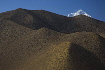 Arrid mountains of Mustang with peak of Nilgiri range visible in background, Lower Mustang, Nepal. November 2004