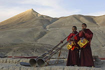 Two Nepalese monks playing the 'Lawa' (long trumpet) on the rooftop of the Chhode Gompa, at the end of the last ceremony of 'Duk chu' festival, Lo-Manthang, Upper Mustang, Nepal