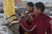 Two Nepalese monks playing the 'Geling' (short trumpet) on rooftop of the Chhode Gompa during 'Duk chu' festival, Lo-Manthang, Upper Mustang, Nepal
