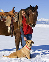Woman with bay Quarter horse gelding and yellow Labrador retreiver, in snow Longmont, Colorado, USA.