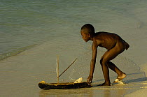Vezo child playing on the beach with model pirogue. Beheloka Vezo fishing village. South-western MADAGASCAR 2005