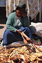 Indian woman selling wooden spoons in market, Pisac, Sacred Valley, Peru 2006.