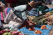 Woman with hat selling carrots in market, Pisac, Sacred Valley, Peru 2006.