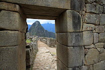 View of Huuauna Picchu through gap in ancient Inca stone wall, Machu Picchu, Peru 2006.