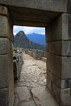View of Huuauna Picchu through gap in ancient Inca stone wall, Machu Picchu, Peru 2006.