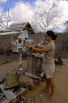 Woman checking Post Office Barrel, Floreana Island, Galapagos Islands, South America