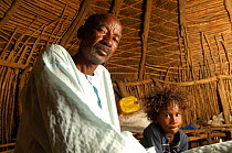 Elderly Fulani man with his grandchild in traditional hut, South Mauritania, West Africa, 2005