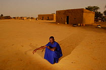 Fulani man sitting in Ari Funda village at dawn, nr Senegal river, South Mauritania, West Africa, 2005