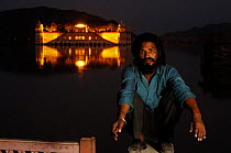 Indian with the Jai Mahal (Lake Palace) in the background floodlit at night, Jaipur, Rajasthan, India 2006