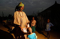 Fulani woman feeding milk to her child at dawn after milking the cattle, North Senegal, West Africa, 2005