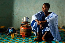 Fulani man brewing tea on calor gas in his house wearing traditional Mauritanian costume, South Mauritania, West Africa, 2005