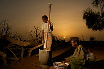 Young Fulani girls grinding seed for flour at dawn, North Senegal, West Africa, 2005