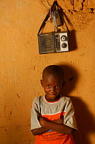 Fulani child sitting beside radio and mobile telephone, portrait, North Senegal, West Africa, 2005