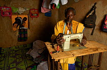Fulani man with sewing machine, making traditional costumes to sell at market, South Mauritania, West Africa, 2005