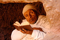 Christian worshipper near St Sauveur's church, Lalibela, North Ethiopia. These worshippers stay for hours in a hole in the carved rock to read their holy books. 2006